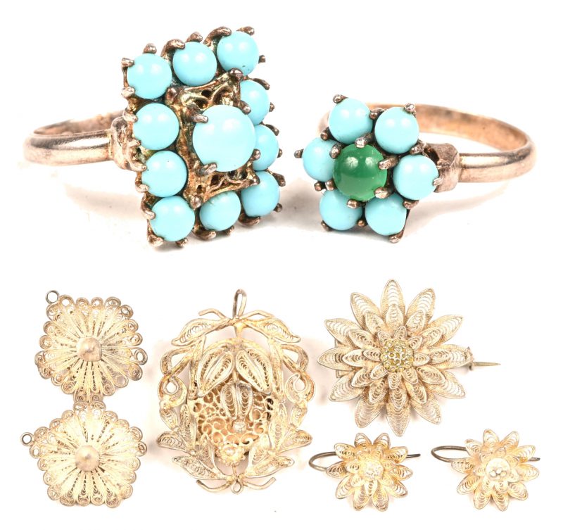 Een lot filigrain zilver bestaande uit oorbellen, broches en hangertjes, toegevoegd 2 zilveren ringen bezet met turquoise.