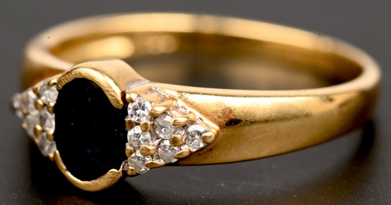 Een 18 kt geelgouden ring bezet met een centrale saffier van +- 0,20 ct. en 12 briljantjes.