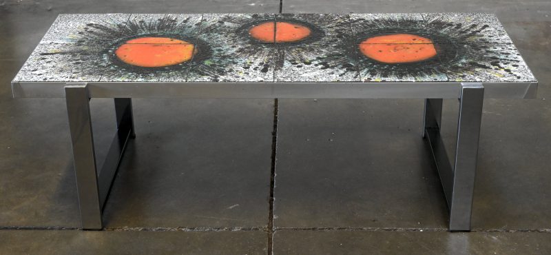 Een vintage salontafel met tegelblad op een verchroomd metalen onderstel. Met een decor van drie oranje sterren op een grijze achtergrond.