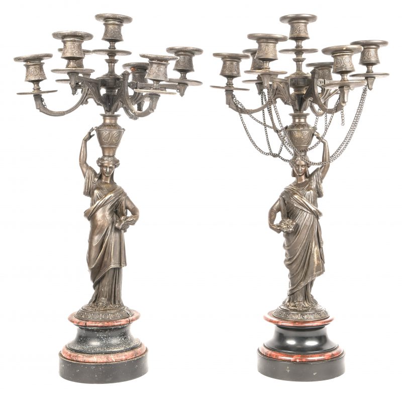 Een paar kandelaars met zeven lichtpunten, gedragen door bronzen kariathiden naar de Griekse oudheid, op rood en zwart gekleurde marmer. Eén voetstuk beschadigd. Einde XIXde eeuw.