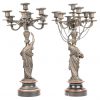 Een paar kandelaars met zeven lichtpunten, gedragen door bronzen kariathiden naar de Griekse oudheid, op rood en zwart gekleurde marmer. Eén voetstuk beschadigd. Einde XIXde eeuw.
