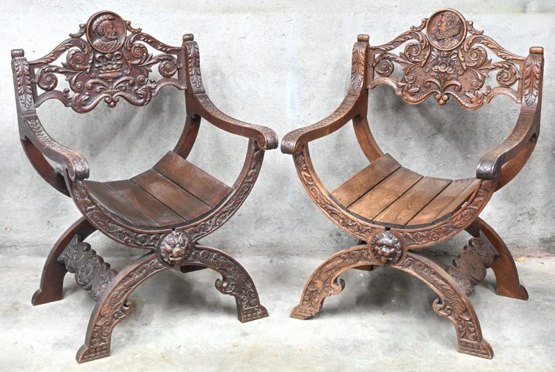 Een paar Savonarola armstoelen van gebeeldhouwd hout. Mooi beeldhouwwerk met guirlandes en een beeldenaar van een man en een vrouw in de rugleuning. Einde XIXde eeuw.