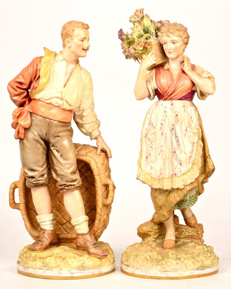 Een paar polychrome beeldjes van porselein en biscuit. Voorstelling van een vrouw met een bloemenmand en een man met een grote lege mand. Onderaan gemerkt, mogelijk Kiyelka, eerste kwart van de XXste eeuw. Minuscule herstelling aan een bloem.
