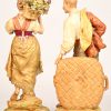 Een paar polychrome beeldjes van porselein en biscuit. Voorstelling van een vrouw met een bloemenmand en een man met een grote lege mand. Onderaan gemerkt, mogelijk Kiyelka, eerste kwart van de XXste eeuw. Minuscule herstelling aan een bloem.