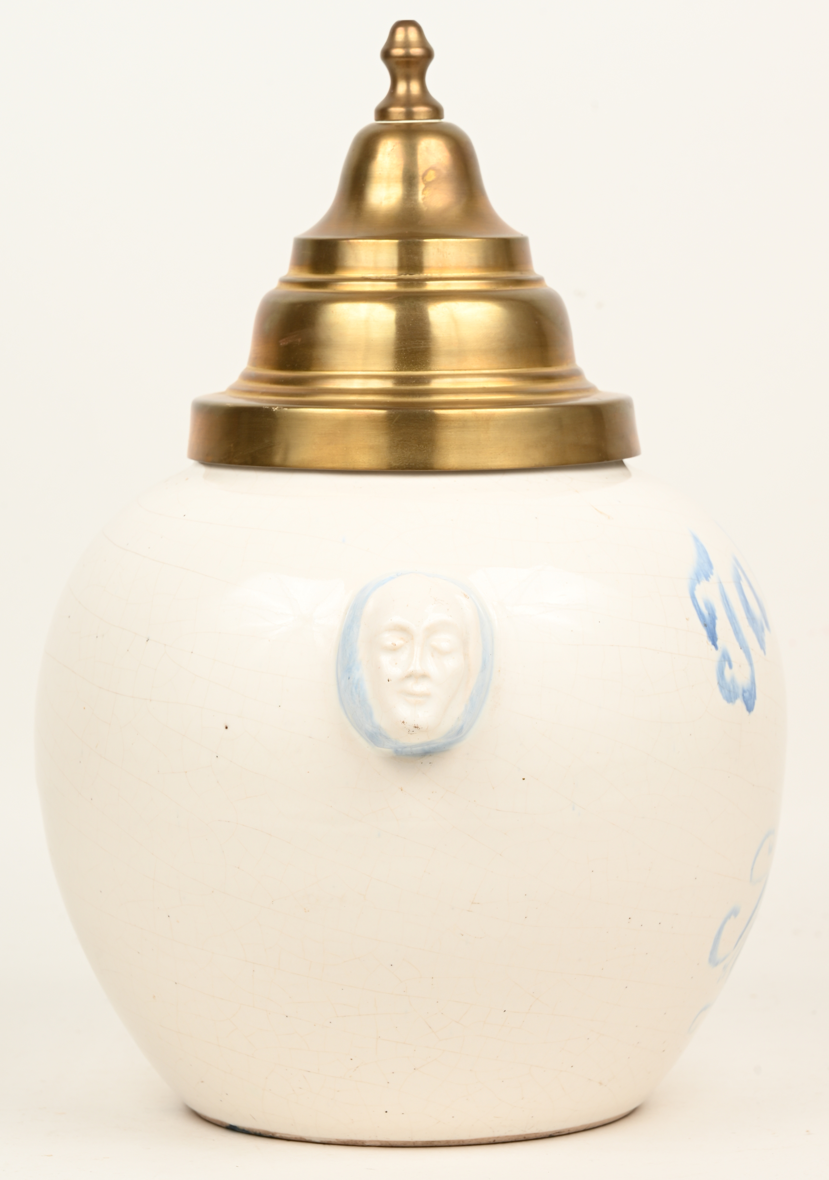 Een porseleinen tabakspot met koperen deksel en gezichten in het handvatreliëf. Opschrift “Tabac au Roy” Een porseleinen tabakspot met koperen deksel en gezichten in het handvatreliëf. Opschrift “Tabac au Roy”.