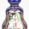Een olielamp van kobaltblauw porselein met bloemendecor en met koperen monturen. Met lampenglas. Op elektriciteit.