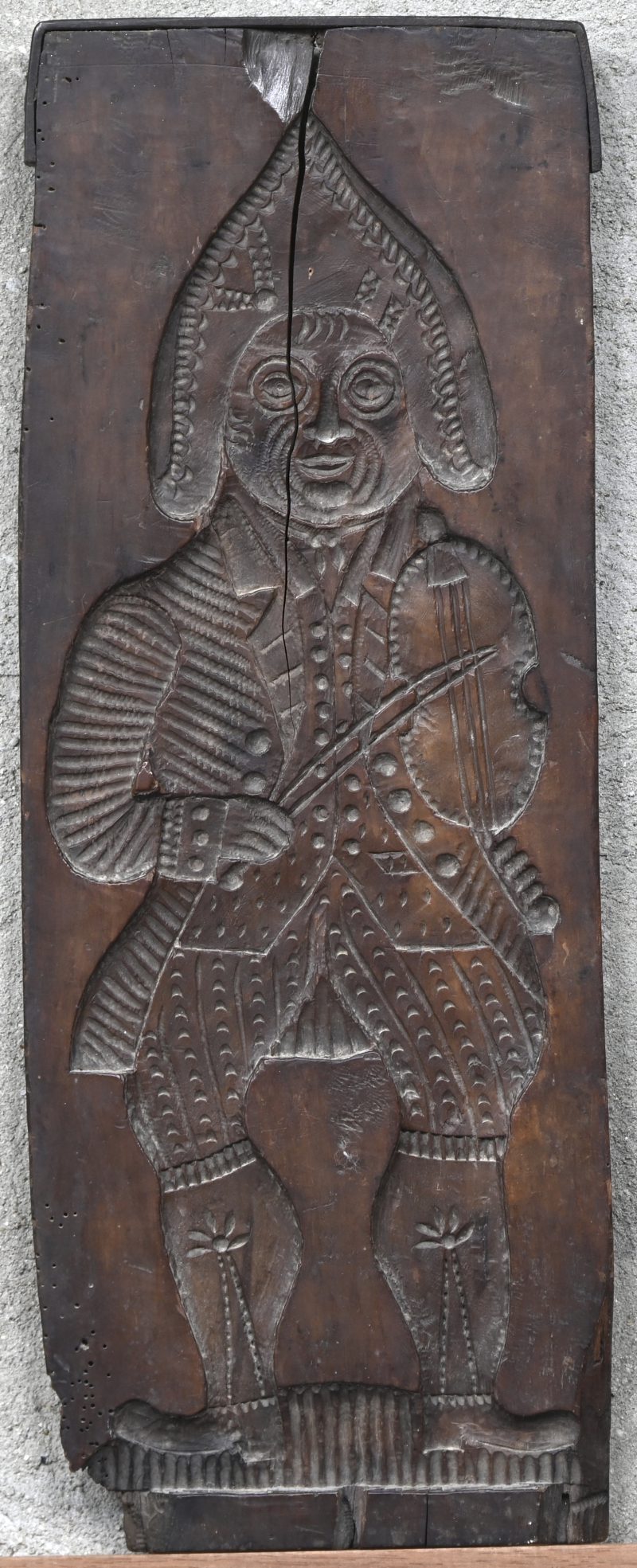 “Violist”. Een oude koekenplank. Bovenaan een barst.