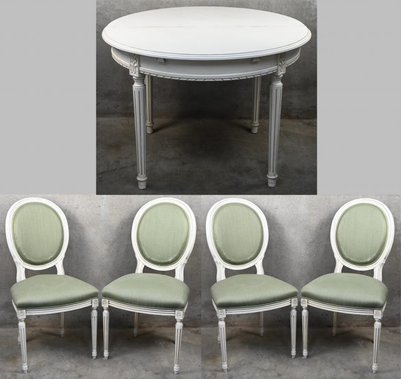 Een ronde verlengbare tafel met vier stoelen in Lodewijk XVI stijl. De stoelen zijn licht gepatineerd met olijfgroene bekleding. De tafel heeft een beetje schade aan het blad.