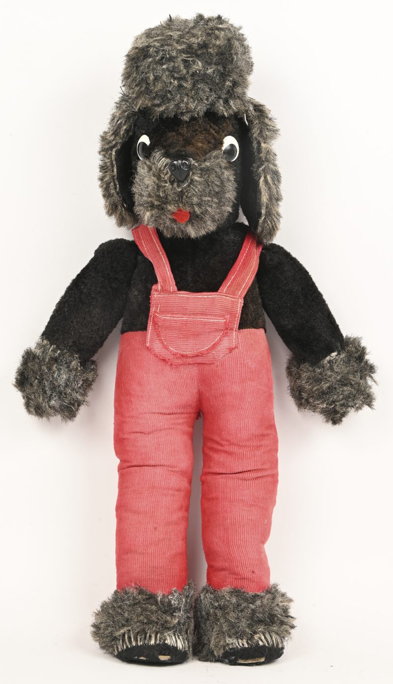 Een vintage pluche poedel knuffel, met rode salopet.