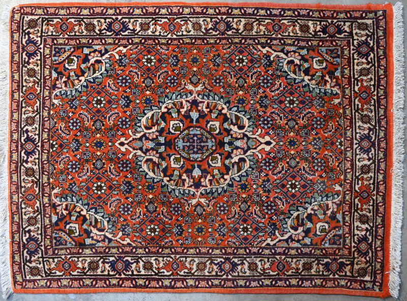 Een wollen karpet versierd met een centraal medaillon. Handgeknoopt.