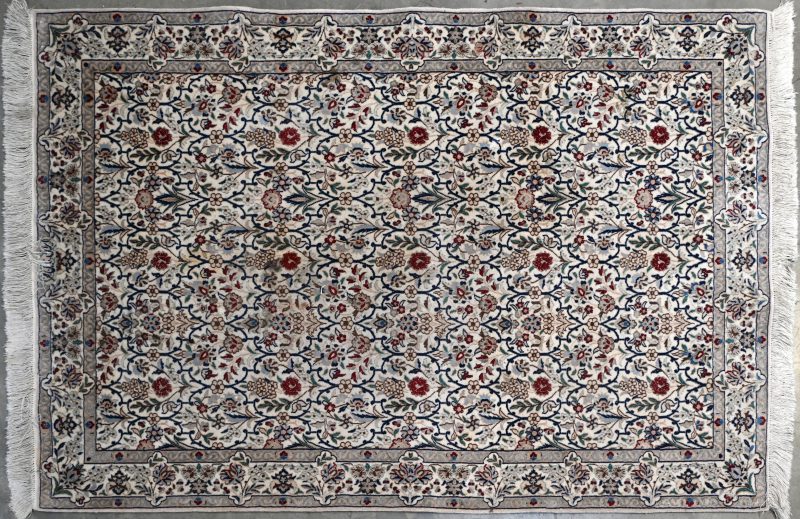 Een Perzisch karpet van wol en zijde met een floraal motief.