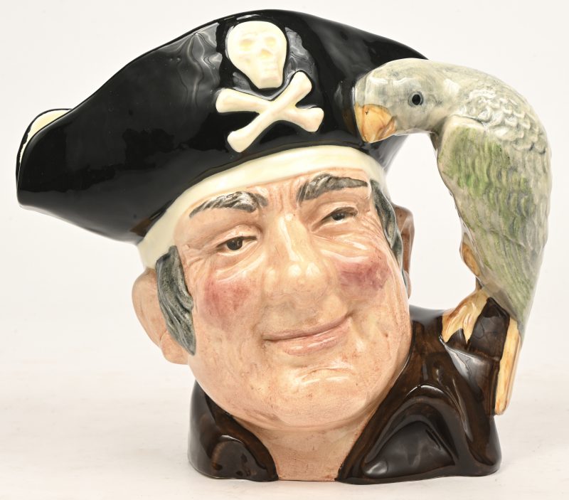Een gekleurde creamware “character jug” in de vorm van het hoofd van Long John Silver met zijn papegaai. Onderaan gemerkt.
