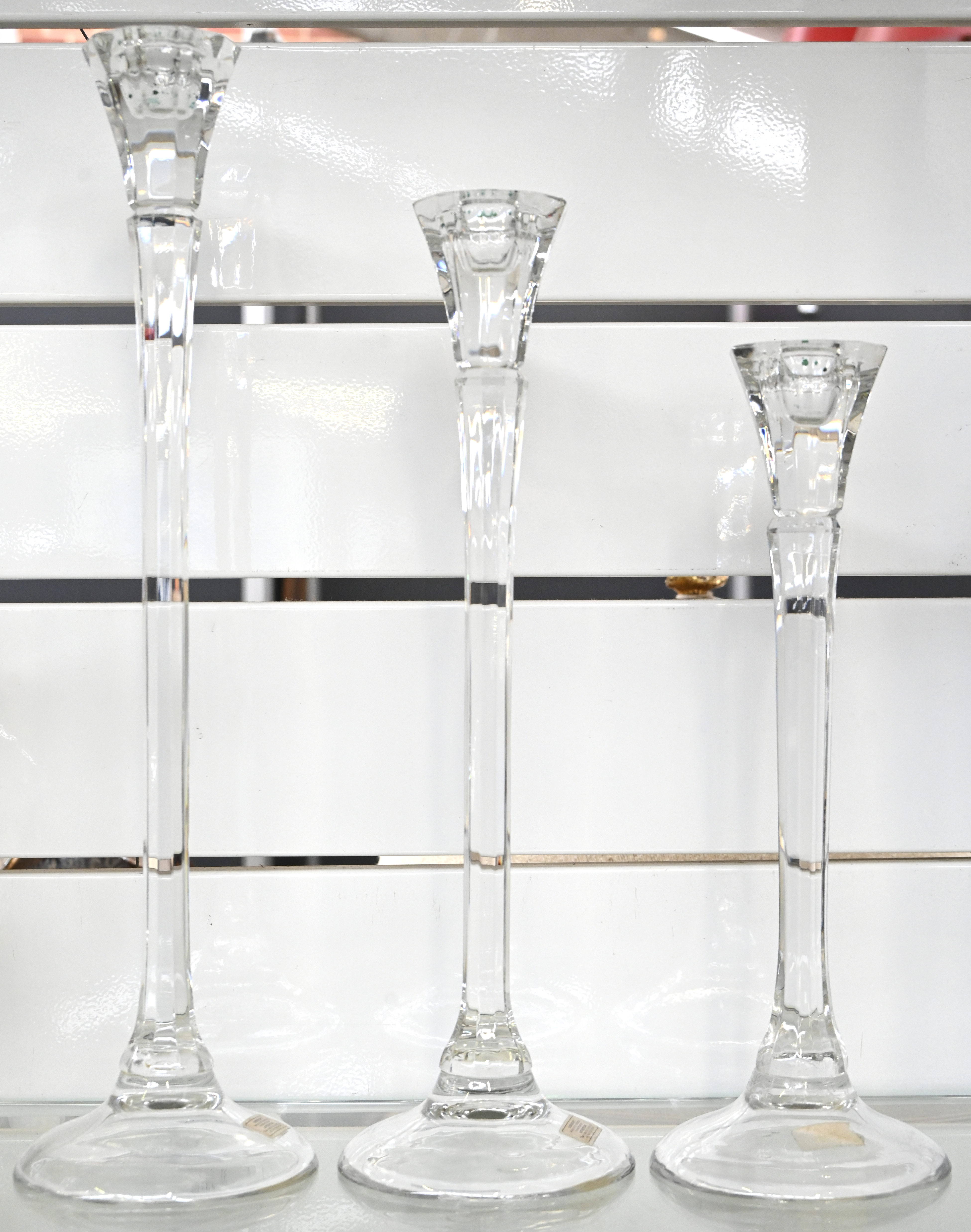 Drie lange kandelaars van kleurloos glas, in lengte afnemend Drie lange kandelaars van kleurloos glas, in lengte afnemend.