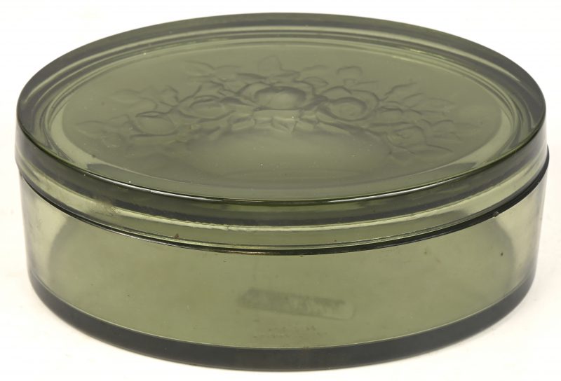 Een ovale doos van gegoten glas, in het deksel voorstelling van een bloemenvaas. Onderaan gemerkt.