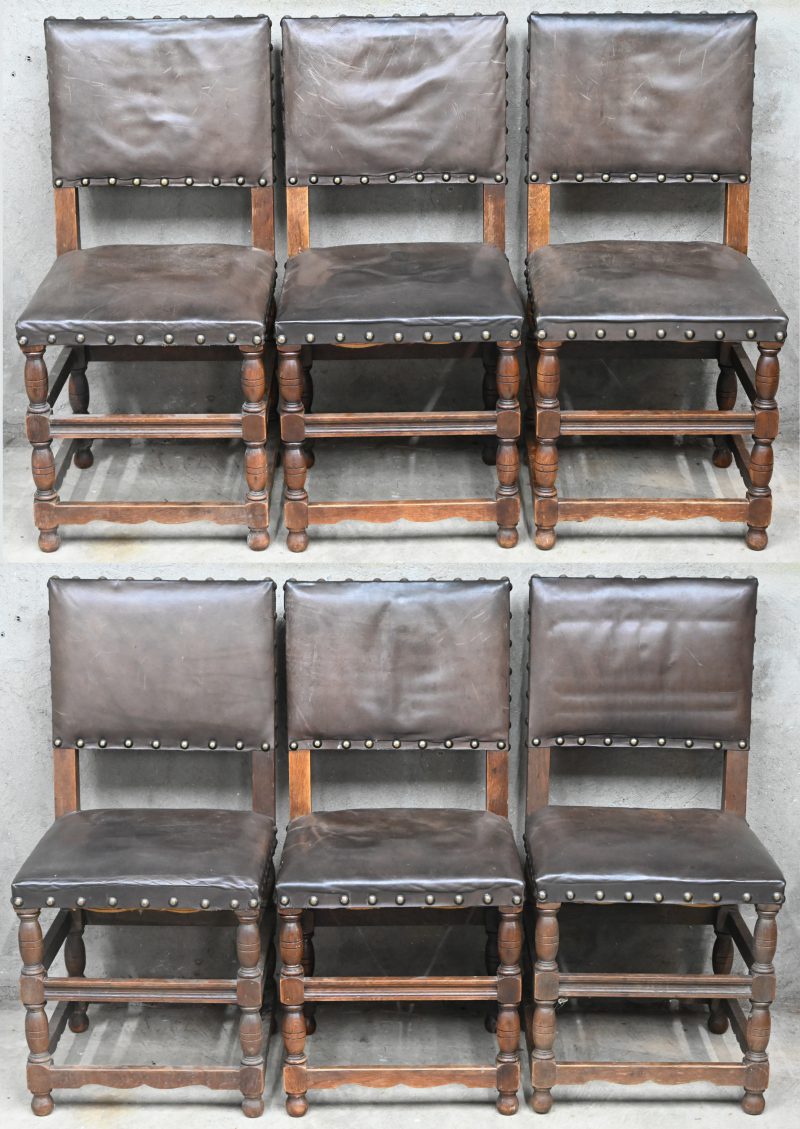 Een reeks van zes eikenhouten stoelen met lederen bekleding met klinknagels.