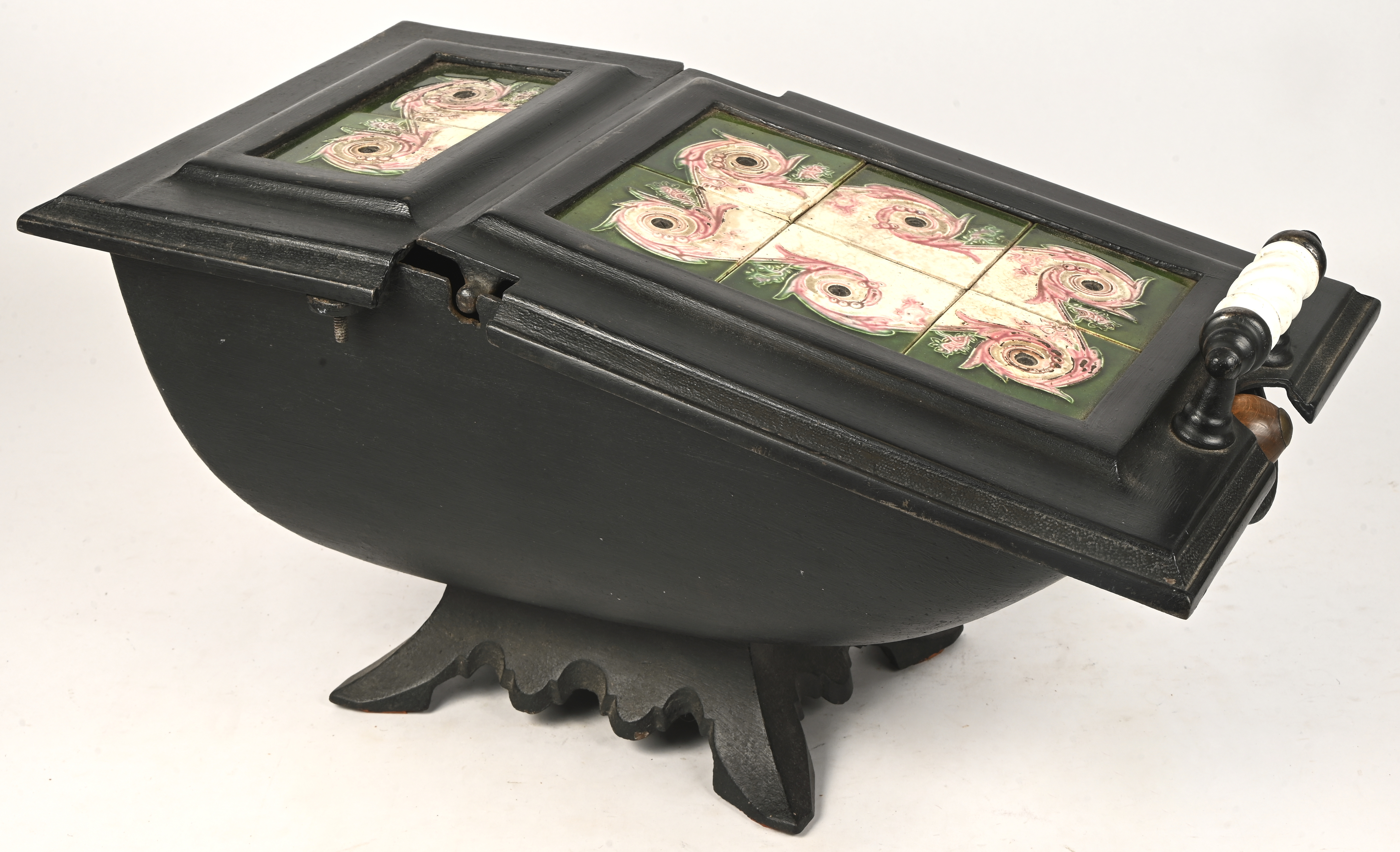 Een antieke gietijzeren kolenkit met aardewerken tegels en een koperen kolenschep Een antieke gietijzeren kolenkit met aardewerken tegels en een koperen kolenschep.