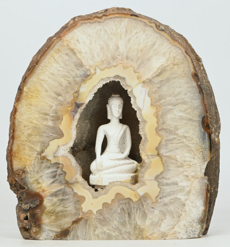 Een grote gepolijste geode met kleine Boeddha binnenin.