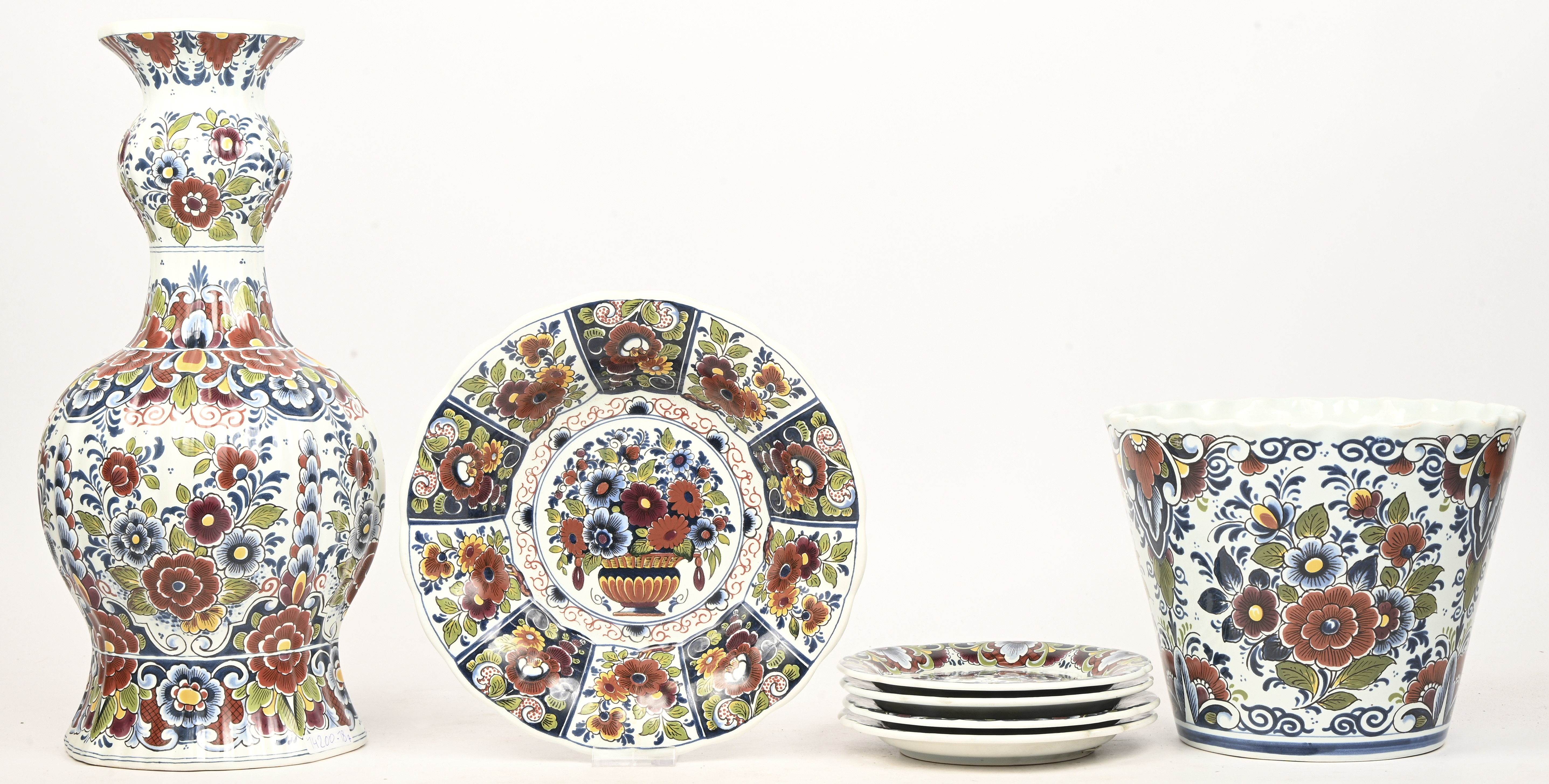 Een set meerkleurig Delfts aardewerk met floraal decor bestaande uit een vaas, een bloempot, een diep bord en 4 kleine bordjes Een set meerkleurig Delfts aardewerk met floraal decor bestaande uit een vaas, een bloempot, een diep bord en 4 kleine bordjes.