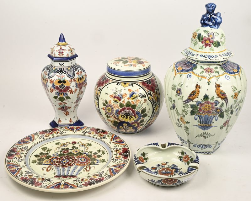 Een set meerkleurig Delfts aardewerk met floraal decor bestaande uit 3 dekselvazen waarvan 2 met haarlijnscheur, een schaal en een asbak.