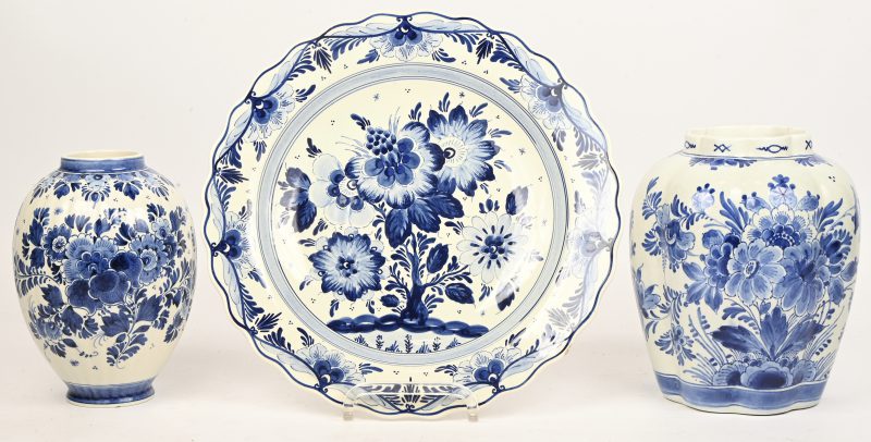 Een lot Delfts blauw aardewerk met floraal decor bestaande uit 2 vazen en een bord. De grootste vaas (Porseleine fles) is gerestaureerd.