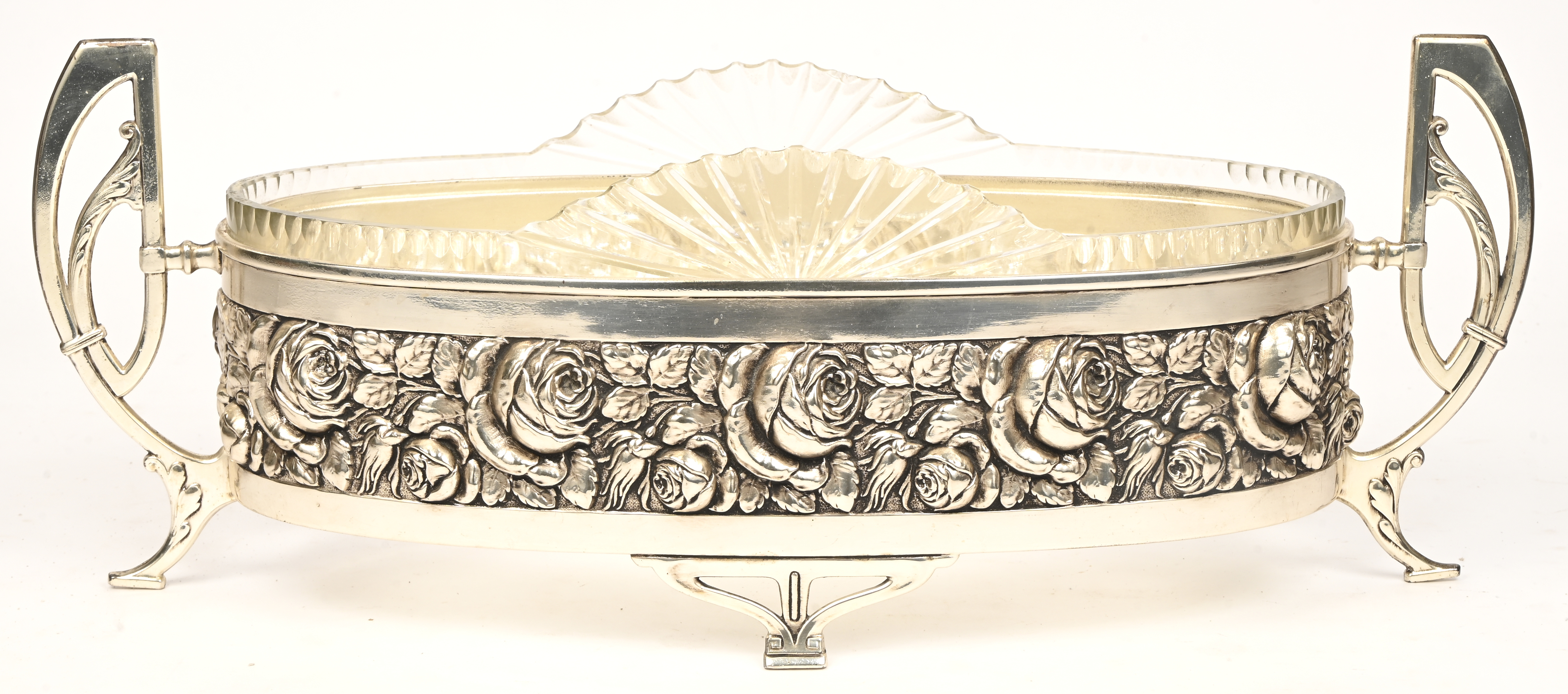 Een milieu de table, verzilverd metaal met een decor van rozen en een geslepen glazen coupe Een milieu de table, verzilverd metaal met een decor van rozen en een geslepen glazen coupe.