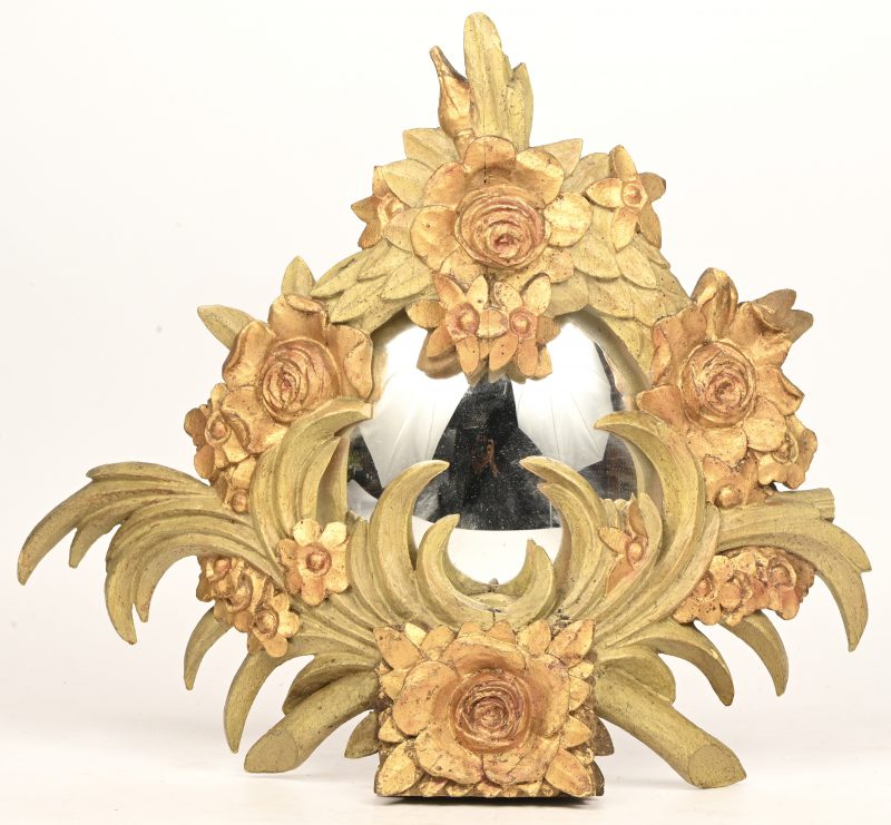 Een houten kastornament met een bolle spiegel. Versierd met goudkleurige bloemen.