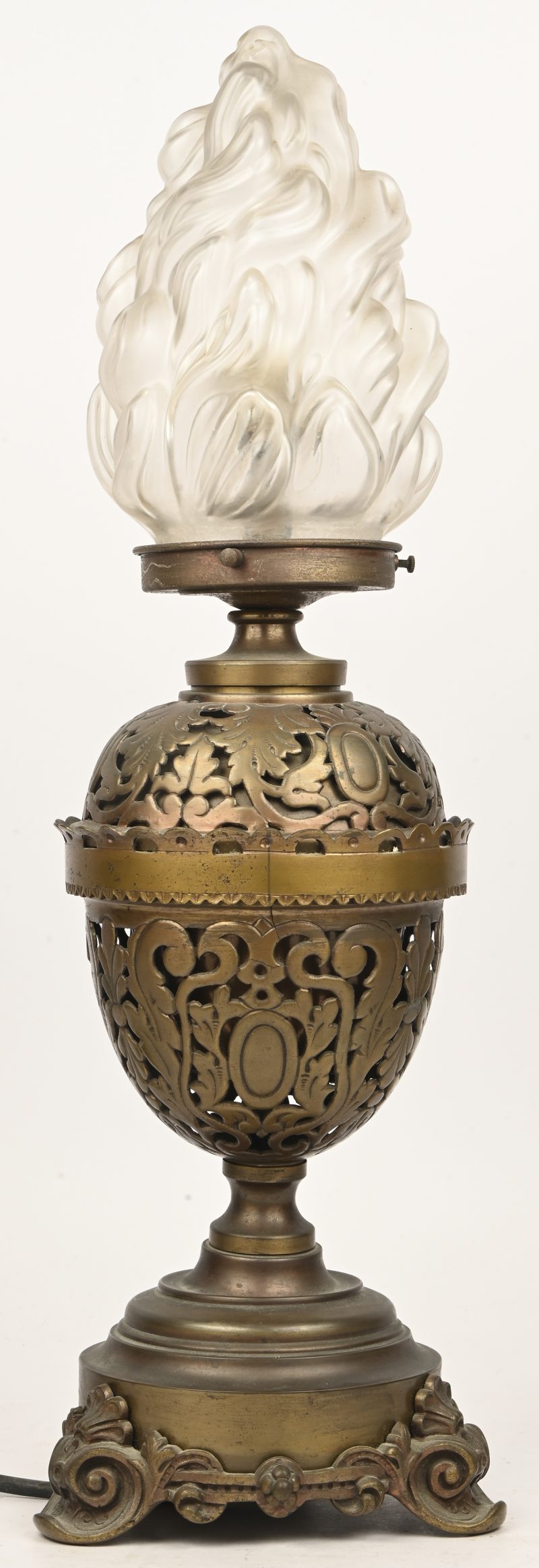 Een bronzen tafellamp met glazen blaker in de vorm van een vlam.
