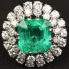Een platina ring bezet met een centrale smaragd van +- 5,15 ct. en diamanten met een gezamenlijk gewicht van +- 1,60 ct.