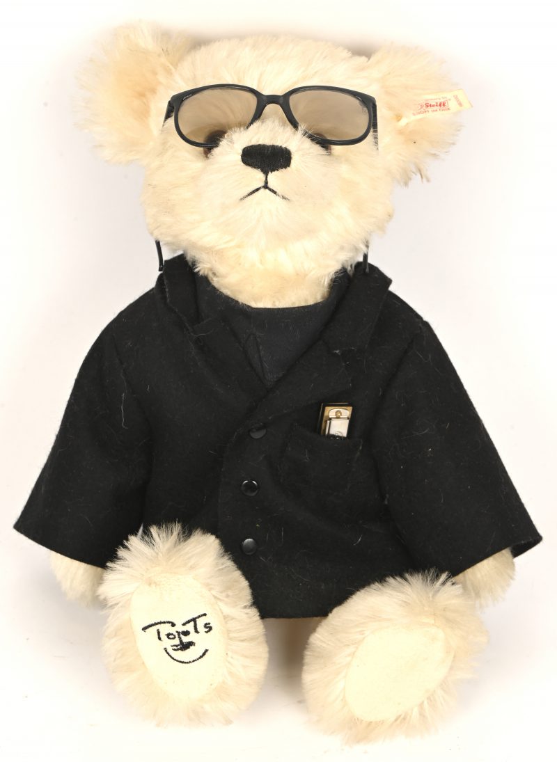‘Toots’, een Steiff beer, opgedragen aan Toots Thielemans. Gemaakt van mohair, 33 cm hoog. Geborduurde snuit en klauwen. De pootjes zijn vervaardigd in vilt met geborduurde handtekening van Toots Thielemans. N° 00135 uit een oplage van 1500 exemplaren.