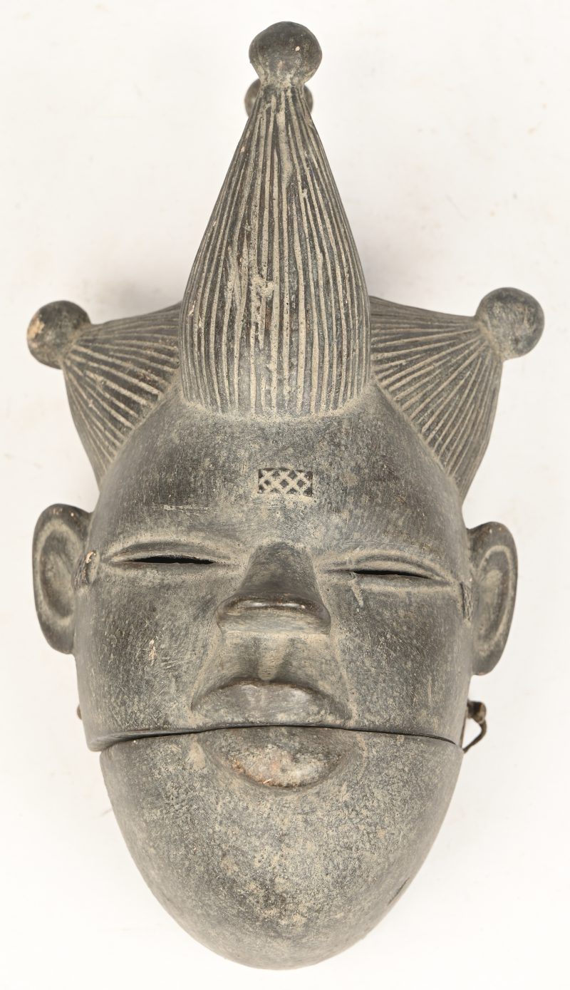 Een gesculpteerd houten masker, Ogoni, Nigeria, met beweegbare mond en metalen tanden.