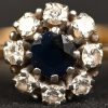Een 18 kt wit- en geelgouden ring bezet met een centrale saffier van +- 0,40 ct. en briljanten met een gezamenlijk gewicht van +- 0,40 ct.