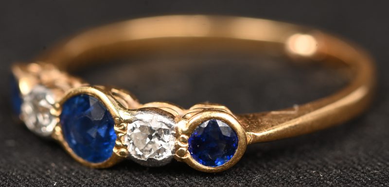 Een 18 kt geelgouden ring bezet met saffieren met een gezamenlijk gewicht van +- 0,40 ct. en met diamanten met een gezamenlijk gewicht van +- 0,20 ct.