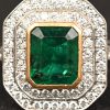 Een 18 kt wit- en geelgouden ring bezet met een centrale Columbiaanse smaragd gewicht van +- 2 ct. en met briljanten met een gezamenlijk gewicht van +- 0,60 ct.