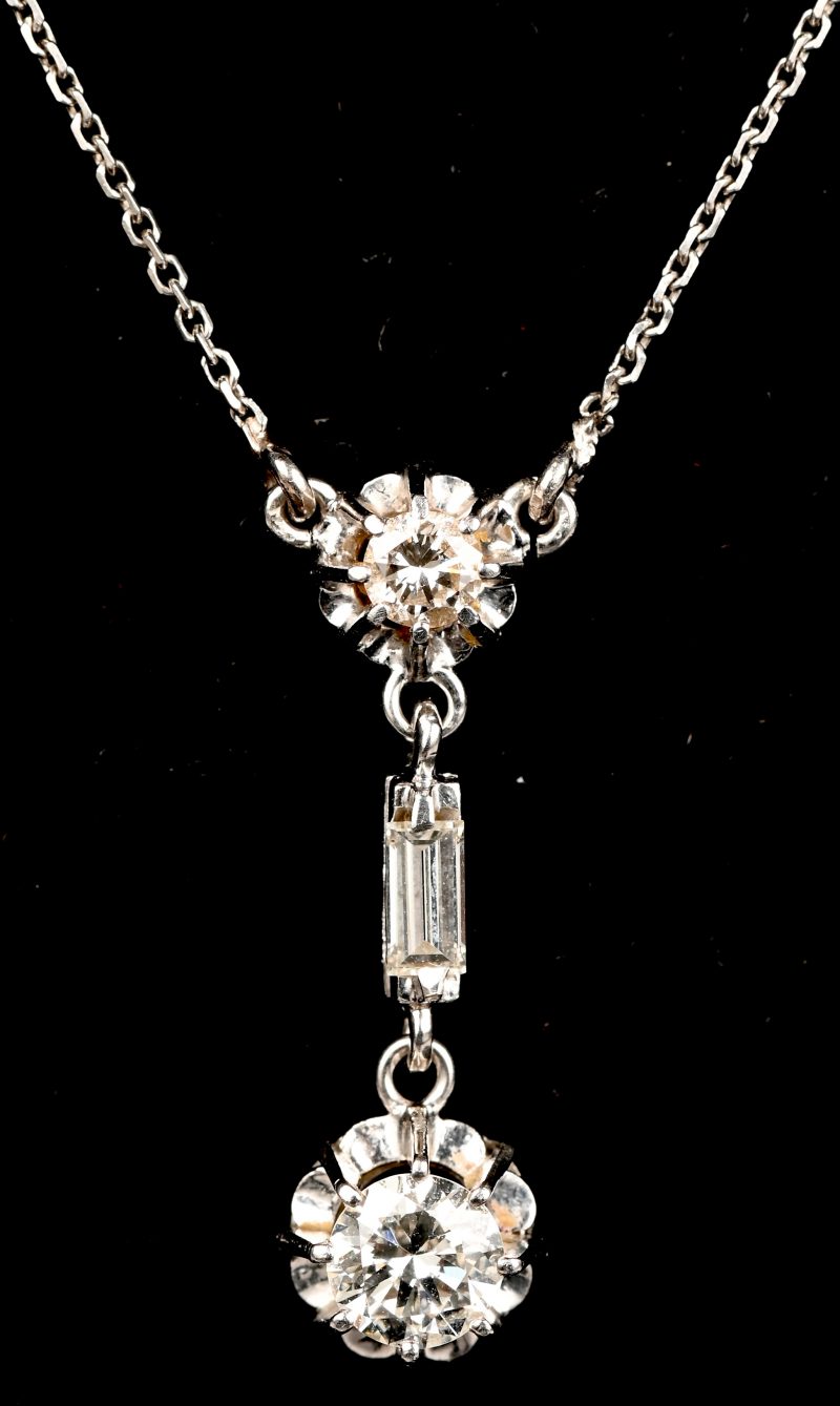 Een 18 kt witgouden ketting met hanger bezet met diamanten en baguettes met een gezamenlijk gewicht van +- 0,60 ct.