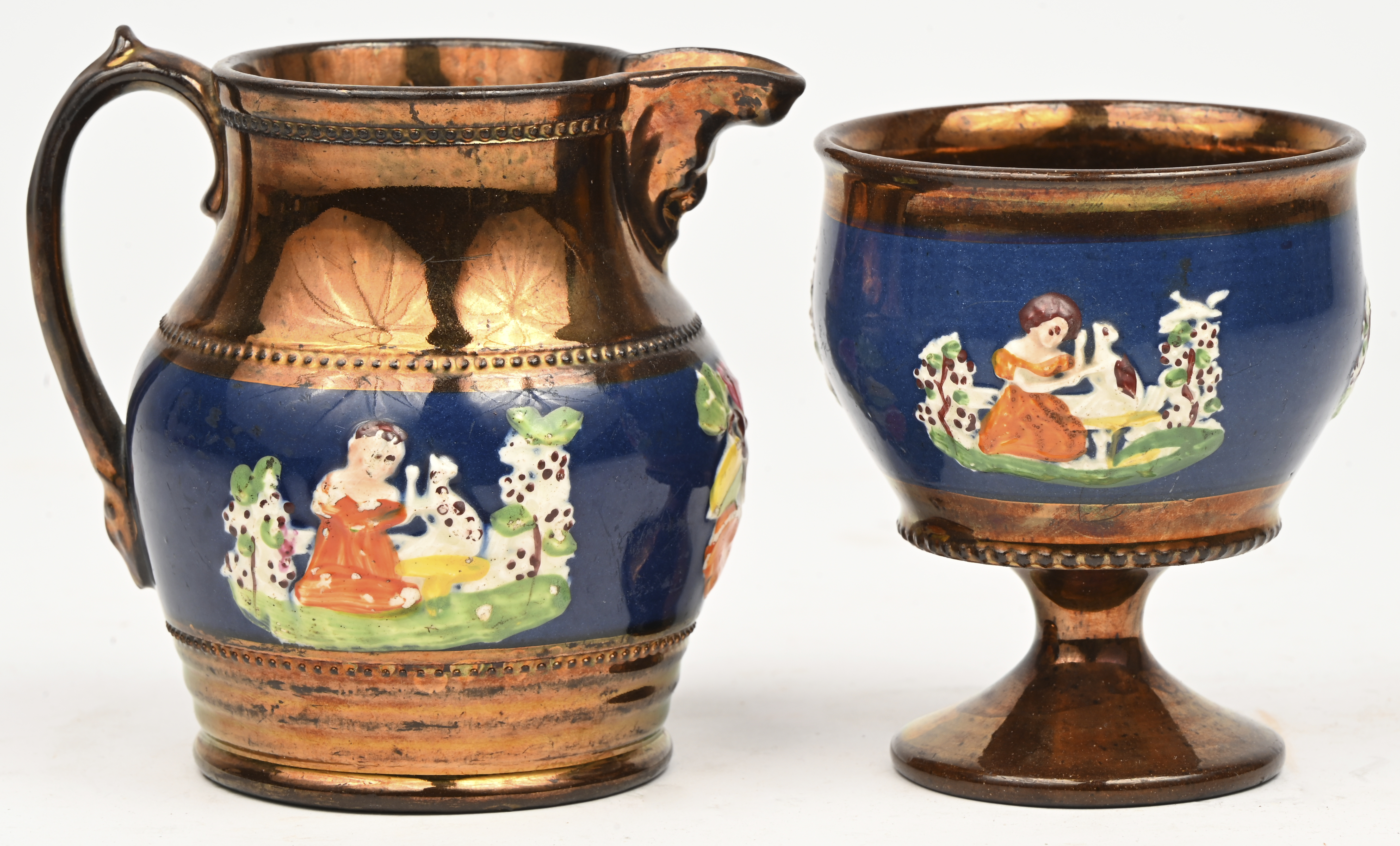 Een lot bestaande uit een antieke keramische Lustreware kan en beker met handgeschilderde decoraties in een klassieke stijl Een lot bestaande uit een antieke keramische Lustreware kan en beker met handgeschilderde decoraties in een klassieke stijl.