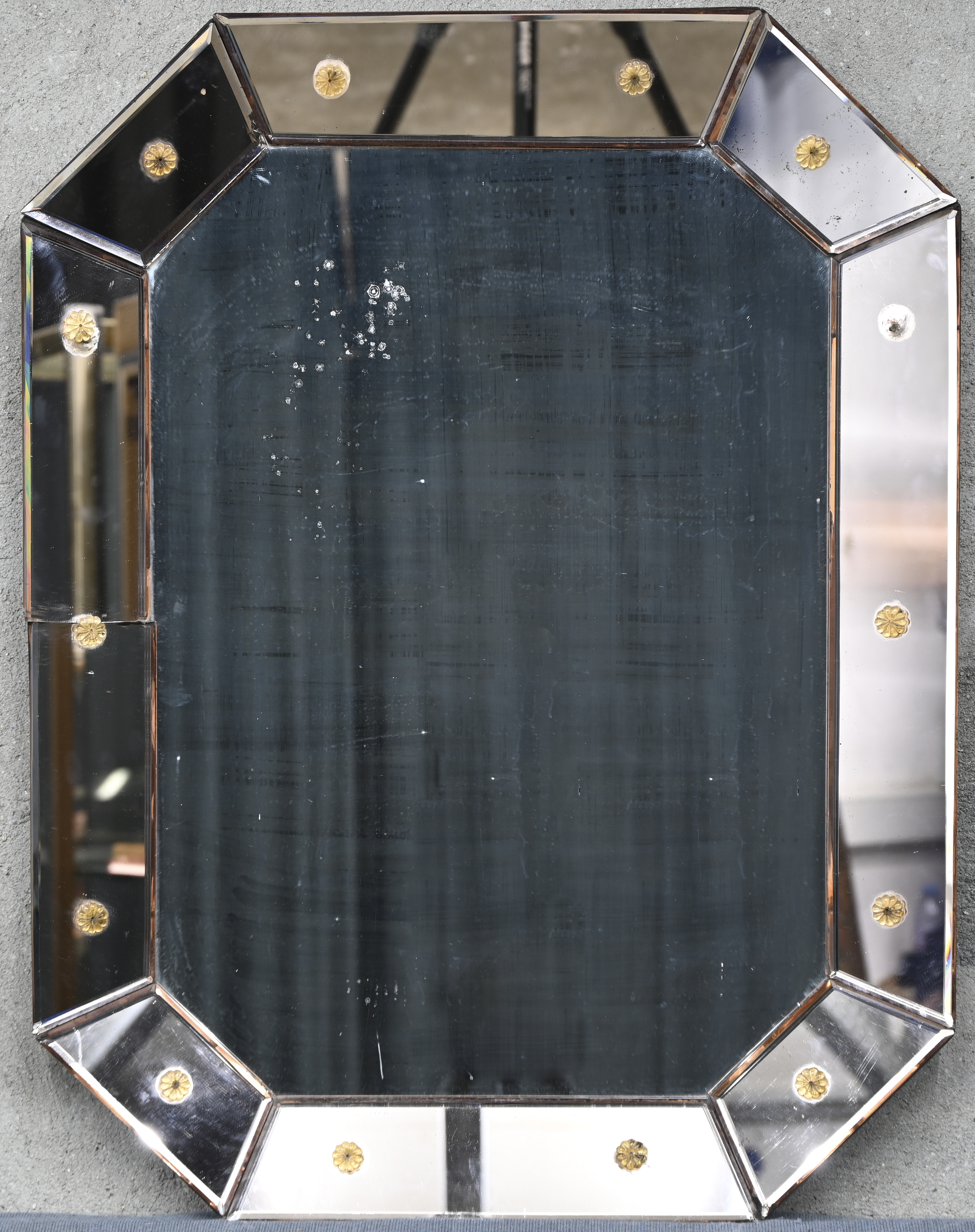 Een Venetiaanse spiegel met geslepen spiegelkader en bloemrozetjes, 1 rozetje ontbreekt en 1 spiegelrand heeft een barst Een Venetiaanse spiegel met geslepen spiegelkader en bloemrozetjes, 1 rozetje ontbreekt en 1 spiegelrand heeft een barst.