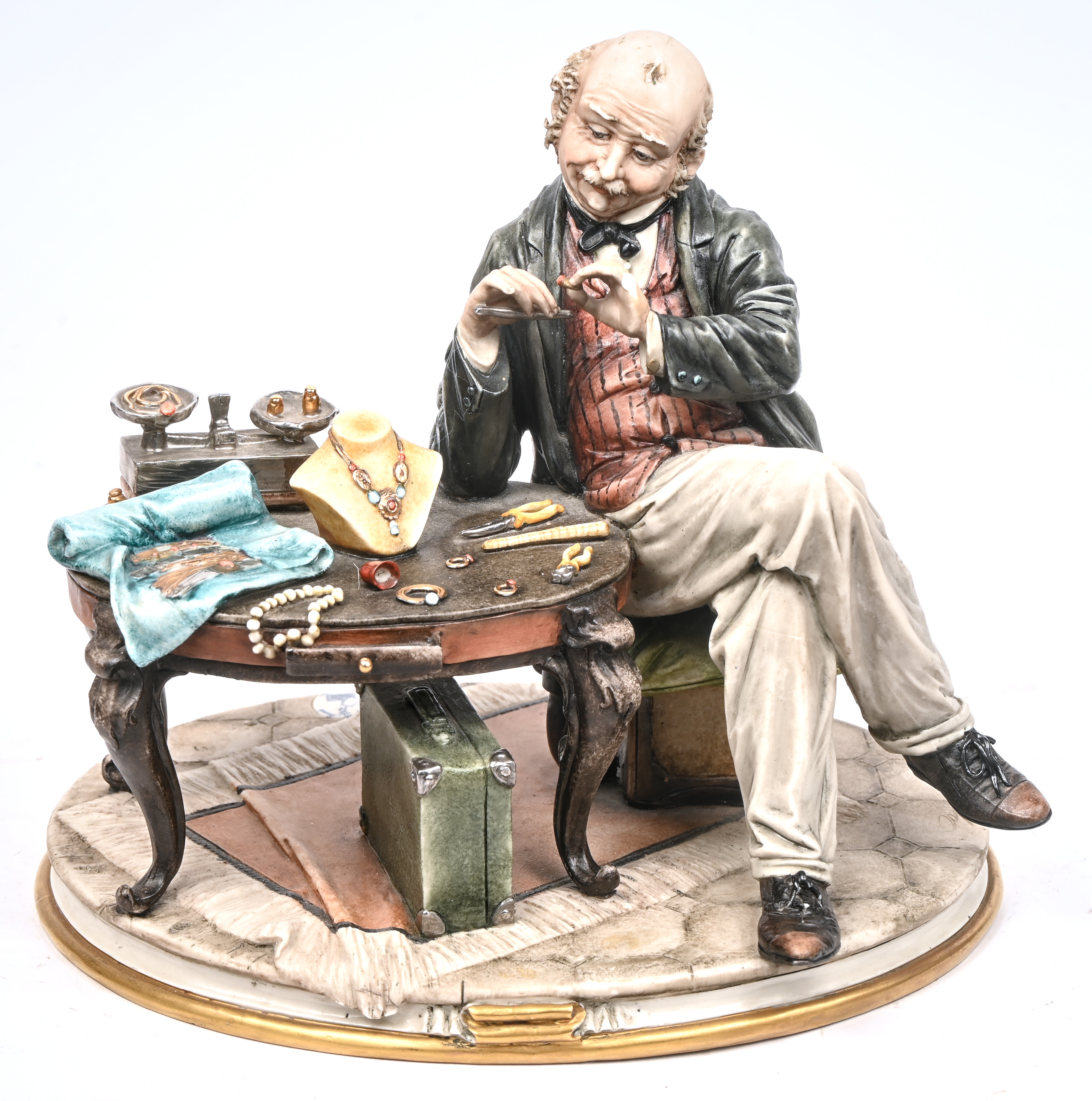 “De Juwelier”. Beeldje van polychroom biscuit. Gemerkt en gesigneerd. Eén vinger ontbreekt “De Juwelier”. Beeldje van polychroom biscuit. Gemerkt en gesigneerd. Eén vinger ontbreekt.