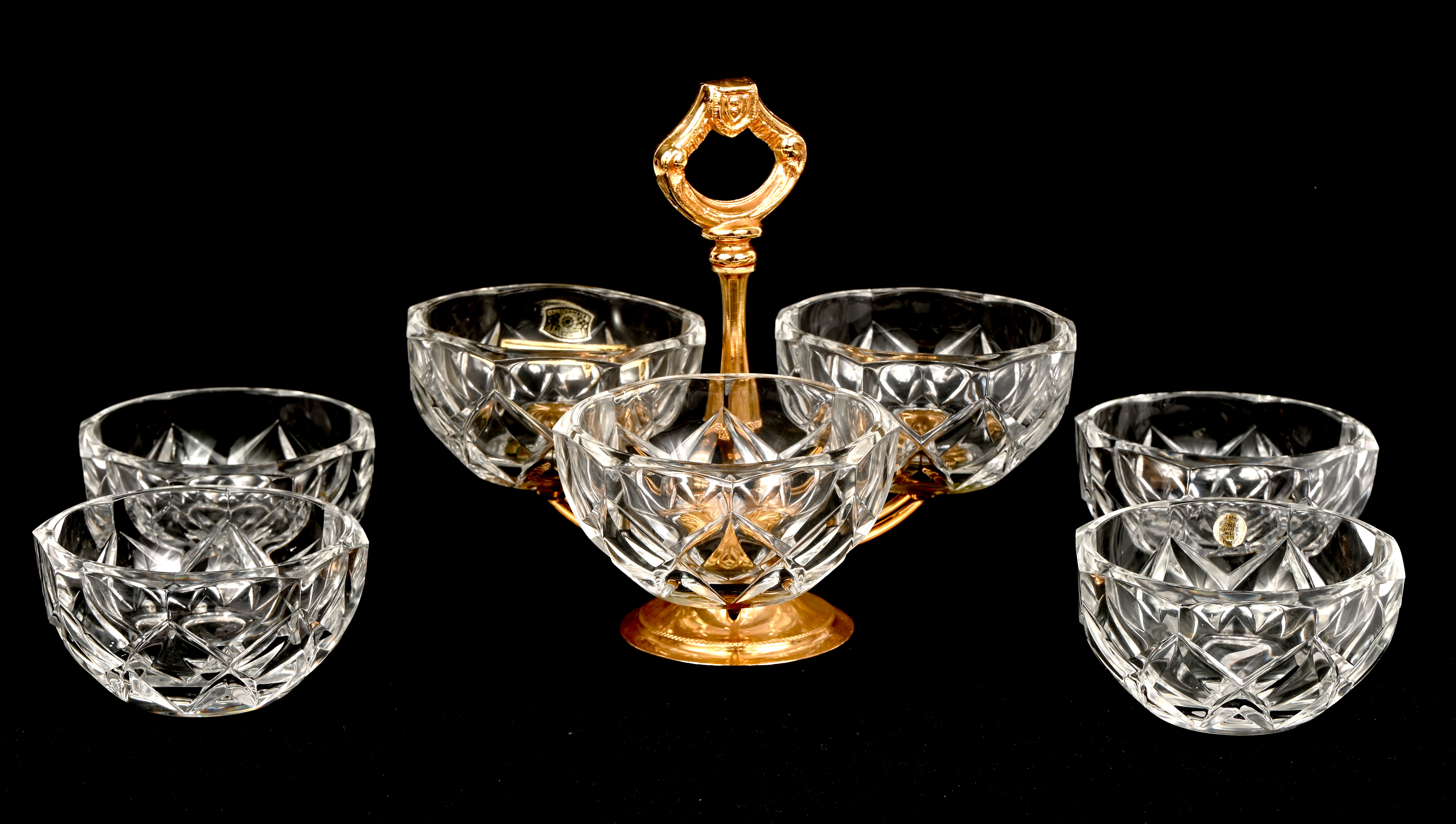 Een specerijenstel bestaande uit een vergulde drievoudige houder met geslepen kristallen rccipiënten, evenals vier bijpassende geslepen kristallen schaaltjes Een specerijenstel bestaande uit een vergulde drievoudige houder met geslepen kristallen rccipiënten, evenals vier bijpassende geslepen kristallen schaaltjes.