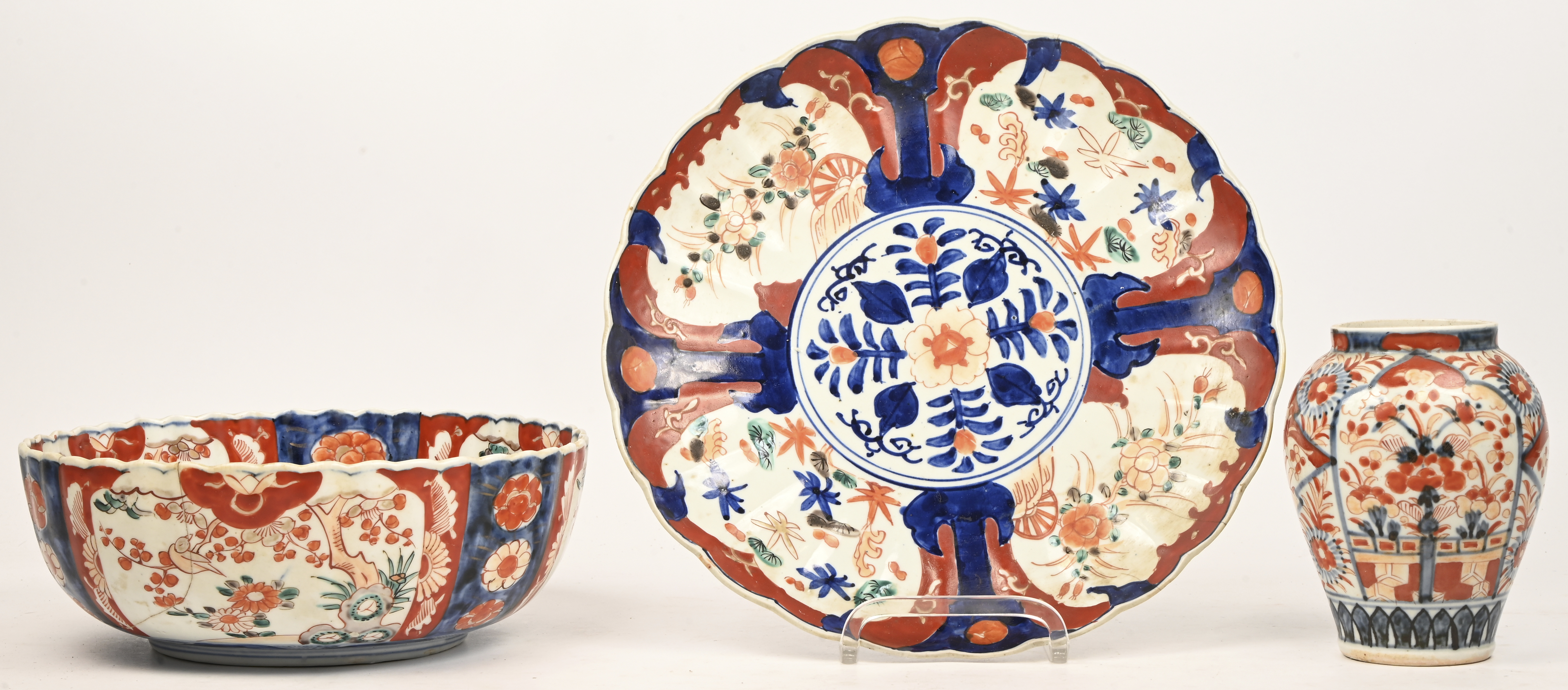 Een grote schotel (30 cm, gebarsten), een coupe (gebarsten) en een klein vaasje van Imari porselein. Eerste helft XXste eeuw Een grote schotel (30 cm, gebarsten), een coupe (gebarsten) en een klein vaasje van Imari porselein. Eerste helft XXste eeuw.