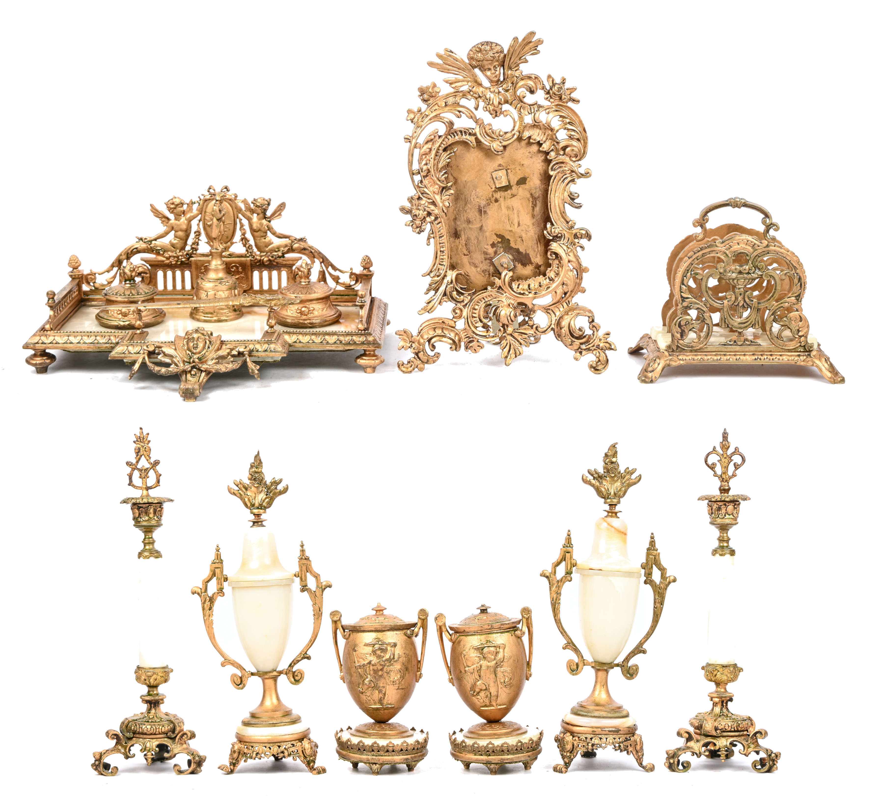 Een bureaugarnituur van goudkleurig metaal en onyx. Bestaande uit een inkstel versierd met een Napoleonbeeldje, een paar penhouders, een paar kandelaars, een paar cassolettes, een brievenhouder, een briefopener, een schemerlamp, een fotolijst. Directoire stijl, medio XXste eeuw Een bureaugarnituur van goudkleurig metaal en onyx. Bestaande uit een inkstel versierd met een Napoleonbeeldje, een paar penhouders, een paar kandelaars, een paar cassolettes, een brievenhouder, een briefopener, een schemerlamp, een fotolijst. Directoire stijl, medio XXste eeuw.