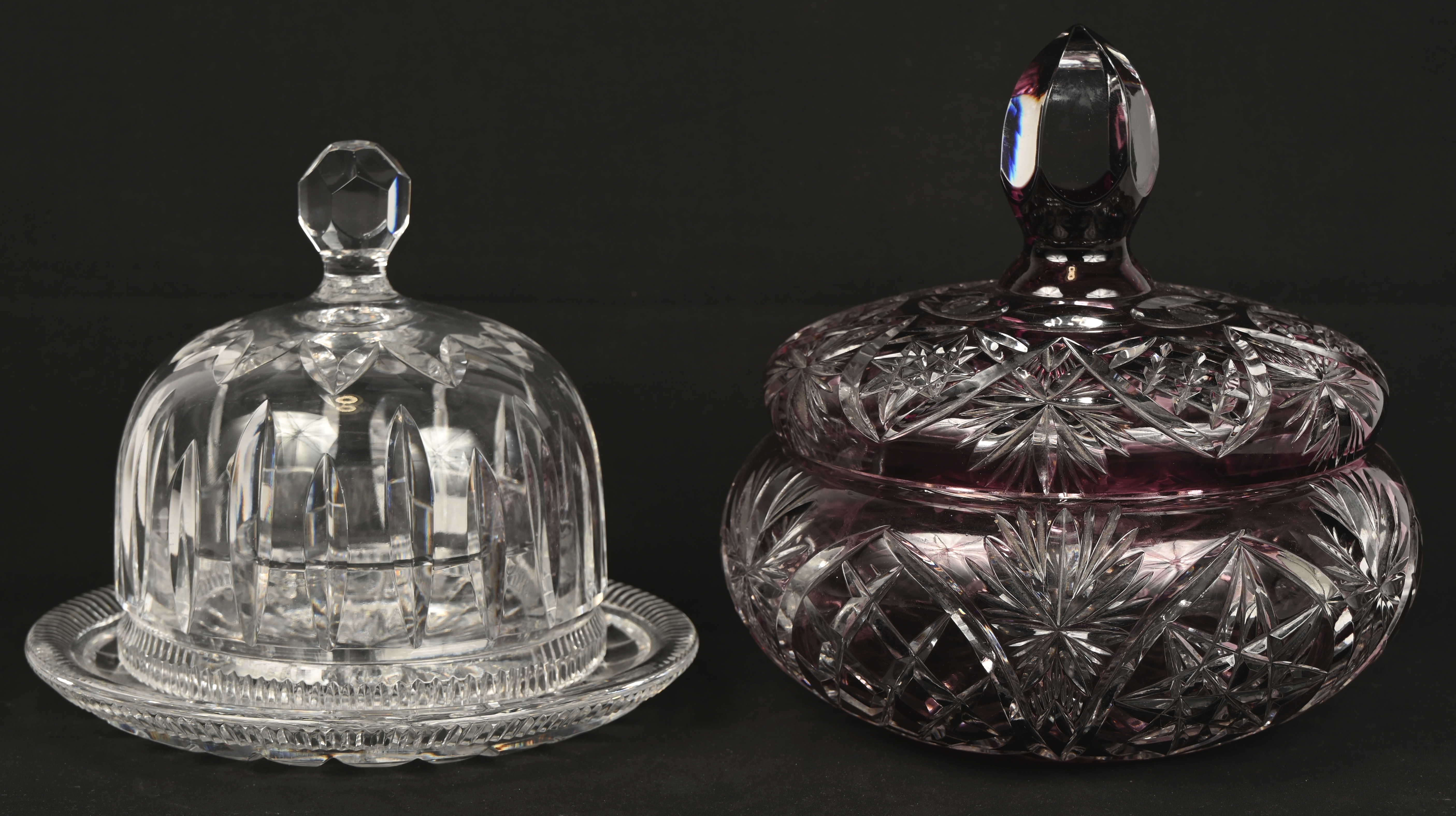 Een gevarieerd lot kleurloos en gekleurd kristal bestaande uit een bonbonniere, twee stolpen waarvan één met voet en een coupe Een gevarieerd lot kleurloos en gekleurd kristal bestaande uit een bonbonniere, twee stolpen waarvan één met voet en een coupe.