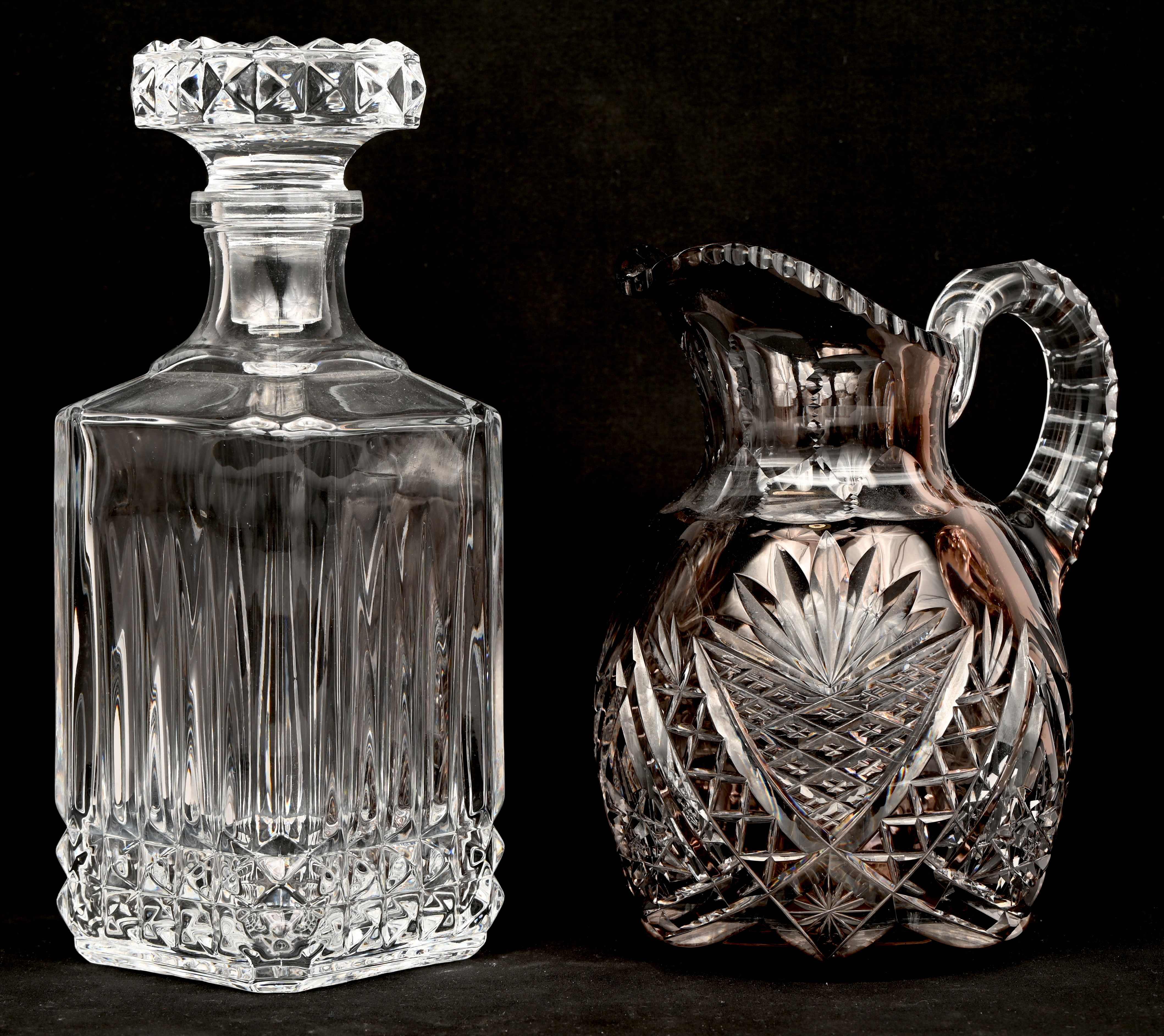 Een gevarieerd lot kleurloos en gekleurd kristal bestaande uit drie karaffen en een schenkkan Een gevarieerd lot kleurloos en gekleurd kristal bestaande uit drie karaffen en een schenkkan.