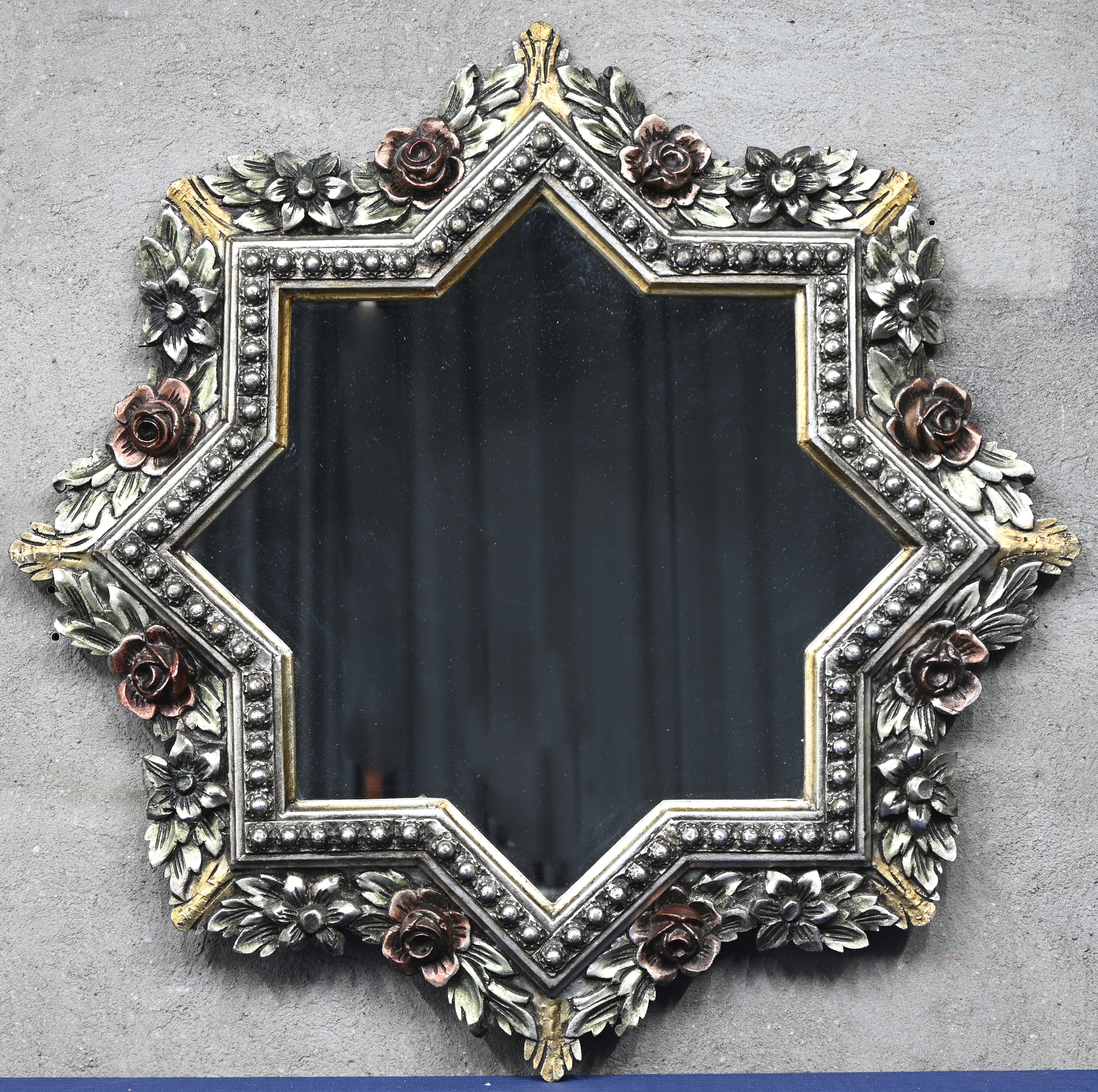 Een stervormige spiegel in een gesculpteerde houten kader, met polychrome beschildering Een stervormige spiegel in een gesculpteerde houten kader, met polychrome beschildering.