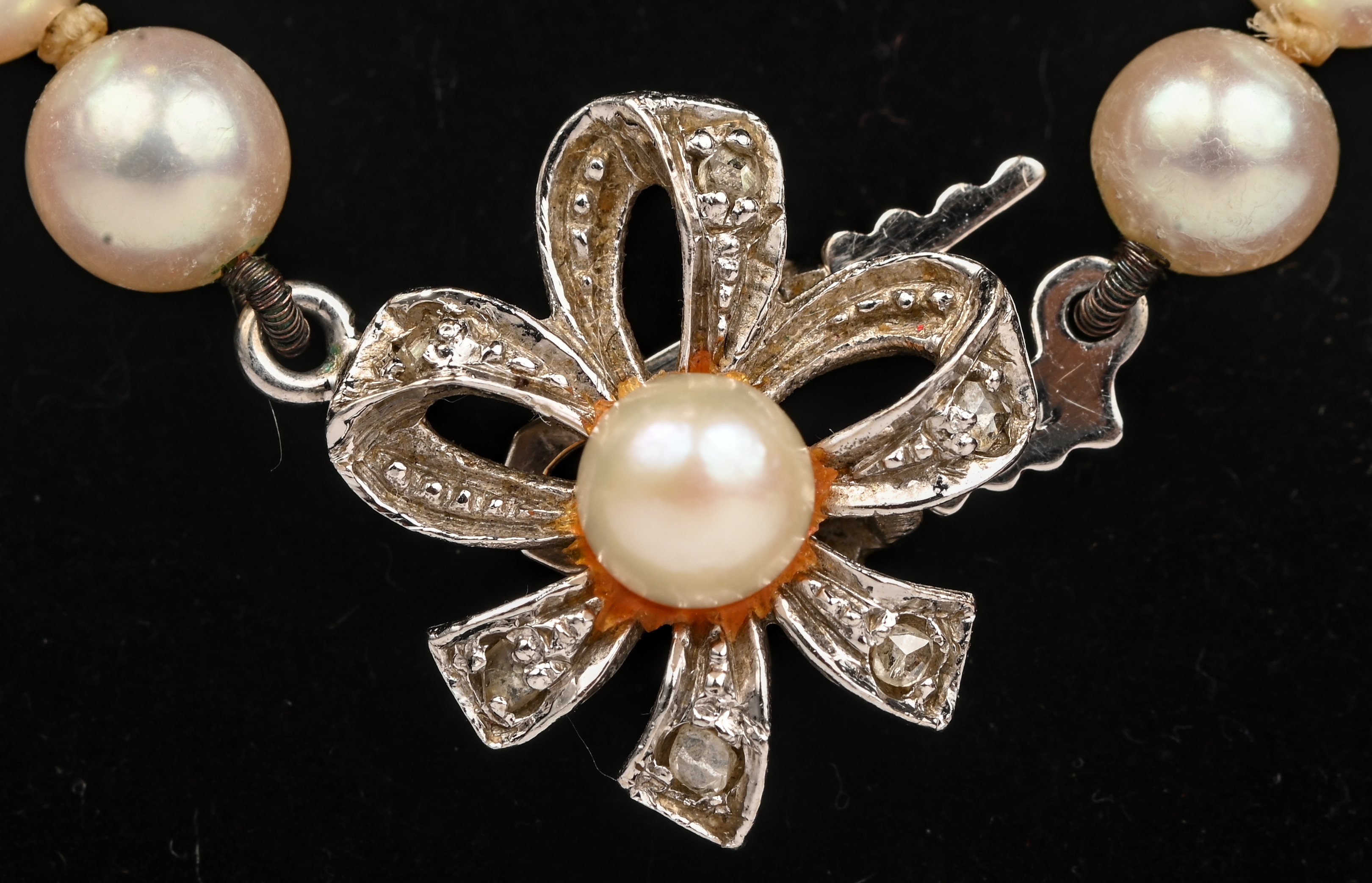 Een parelhalssnoer met 18 kt witgouden bloemvormig slot bezet met zes diamantjes oude slijp Een parelhalssnoer met 18 kt witgouden bloemvormig slot bezet met zes diamantjes oude slijp.