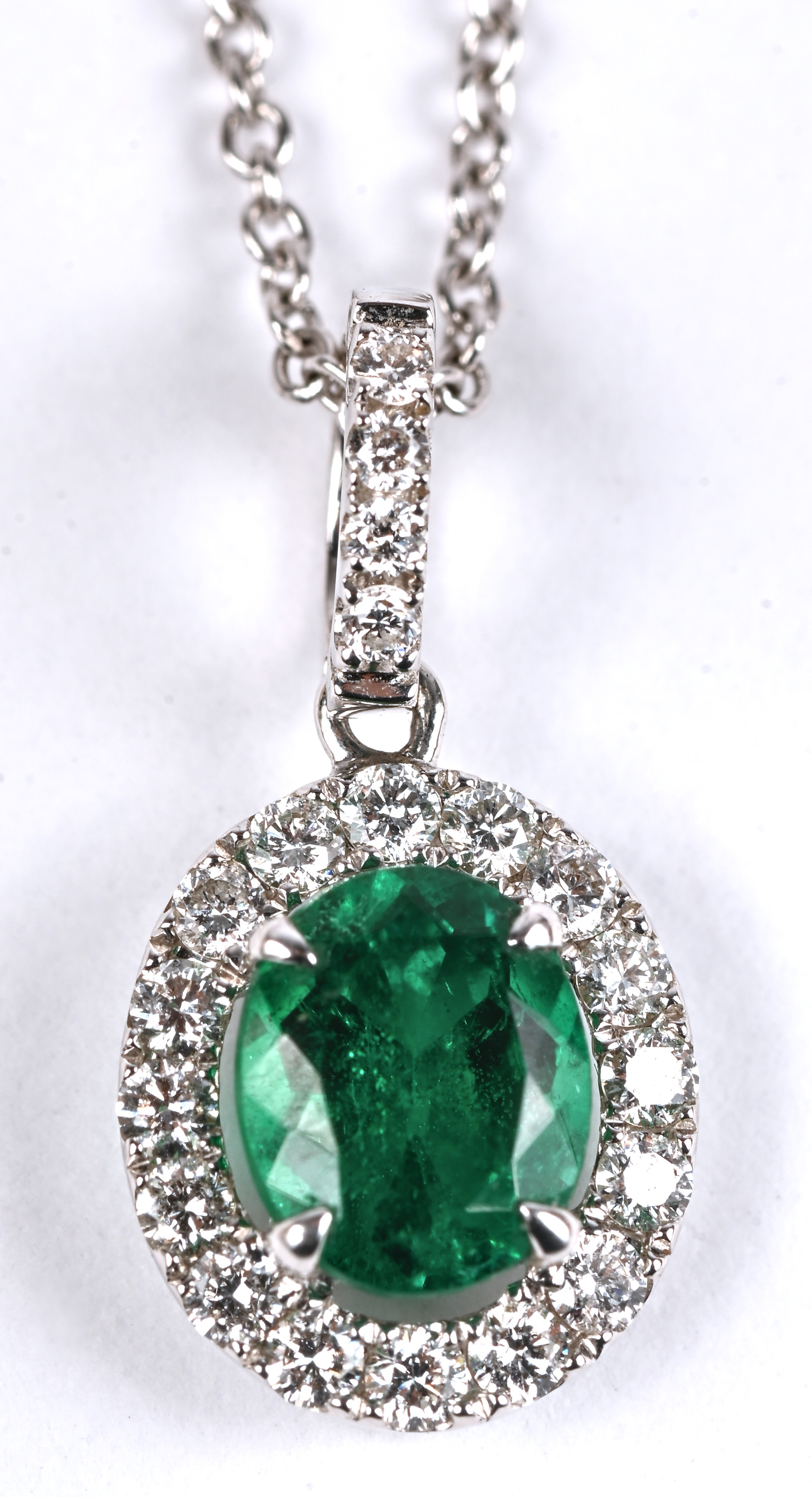 Een 18 kt witgouden ketting met hanger bezet met centrale smaragd 1,12 ct en briljanten van een gezamenlijk gewicht van 0,21 ct Een 18 kt witgouden ketting met hanger bezet met centrale smaragd 1,12 ct en briljanten van een gezamenlijk gewicht van 0,21 ct.