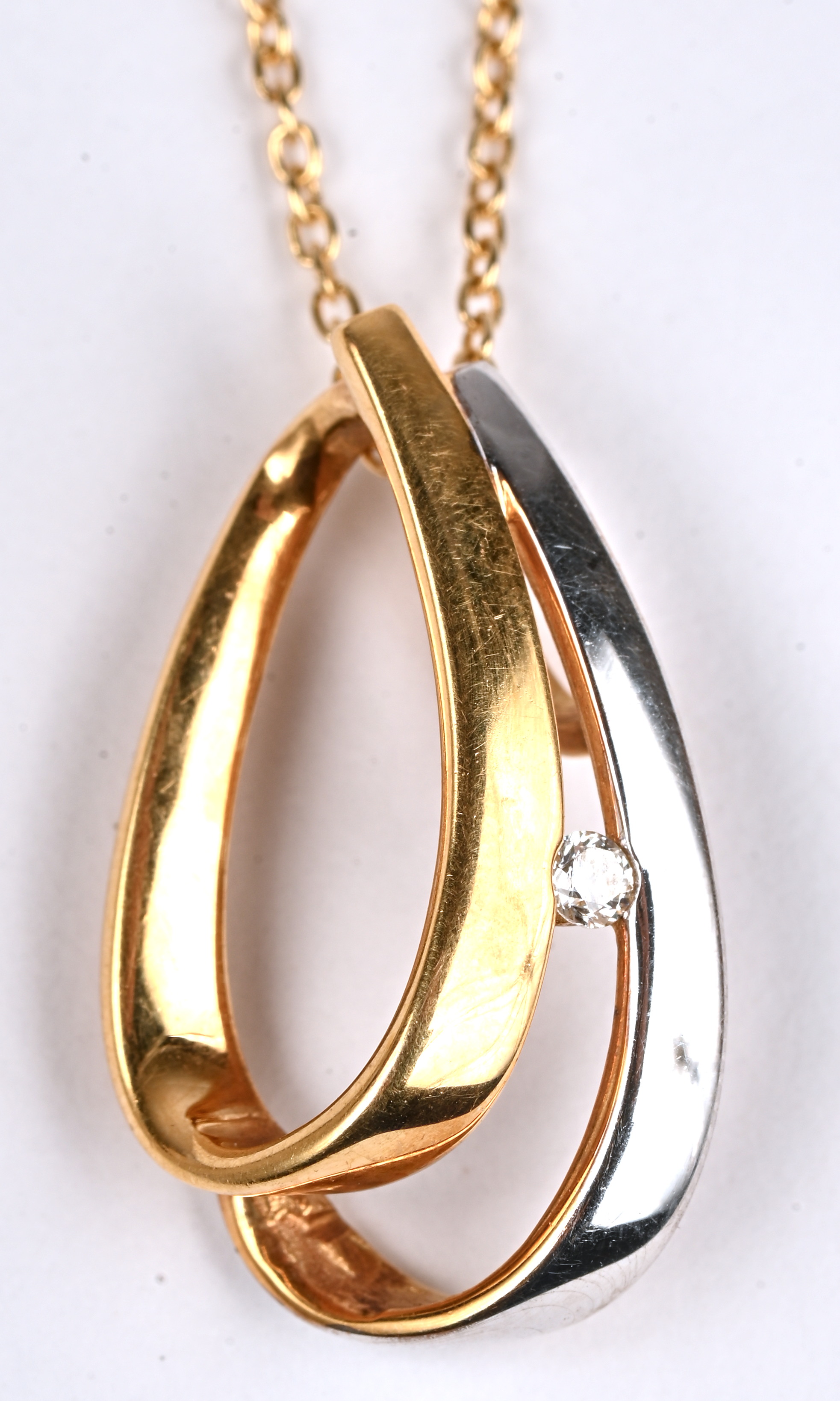 Een 18 kt geelgouden ketting met wit- en geelgouden hanger bezet met briljanten van een gezamenlijk gewicht van 0,06 ct Een 18 kt geelgouden ketting met wit- en geelgouden hanger bezet met briljanten van een gezamenlijk gewicht van 0,06 ct.