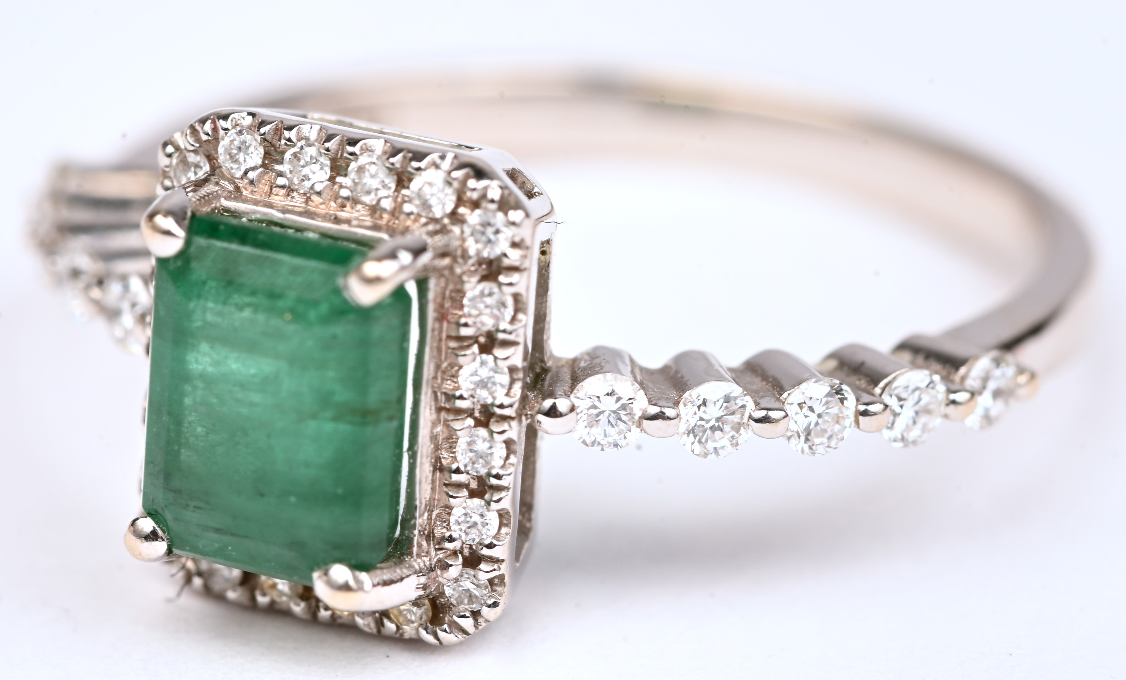 Een 18 kt witgouden ring bezet met een centrale smaragd van +- 0,50 ct. en briljanten met een gezamenlijk gewicht van +- 0,25 ct Een 18 kt witgouden ring bezet met een centrale smaragd van +- 0,50 ct. en briljanten met een gezamenlijk gewicht van +- 0,25 ct.