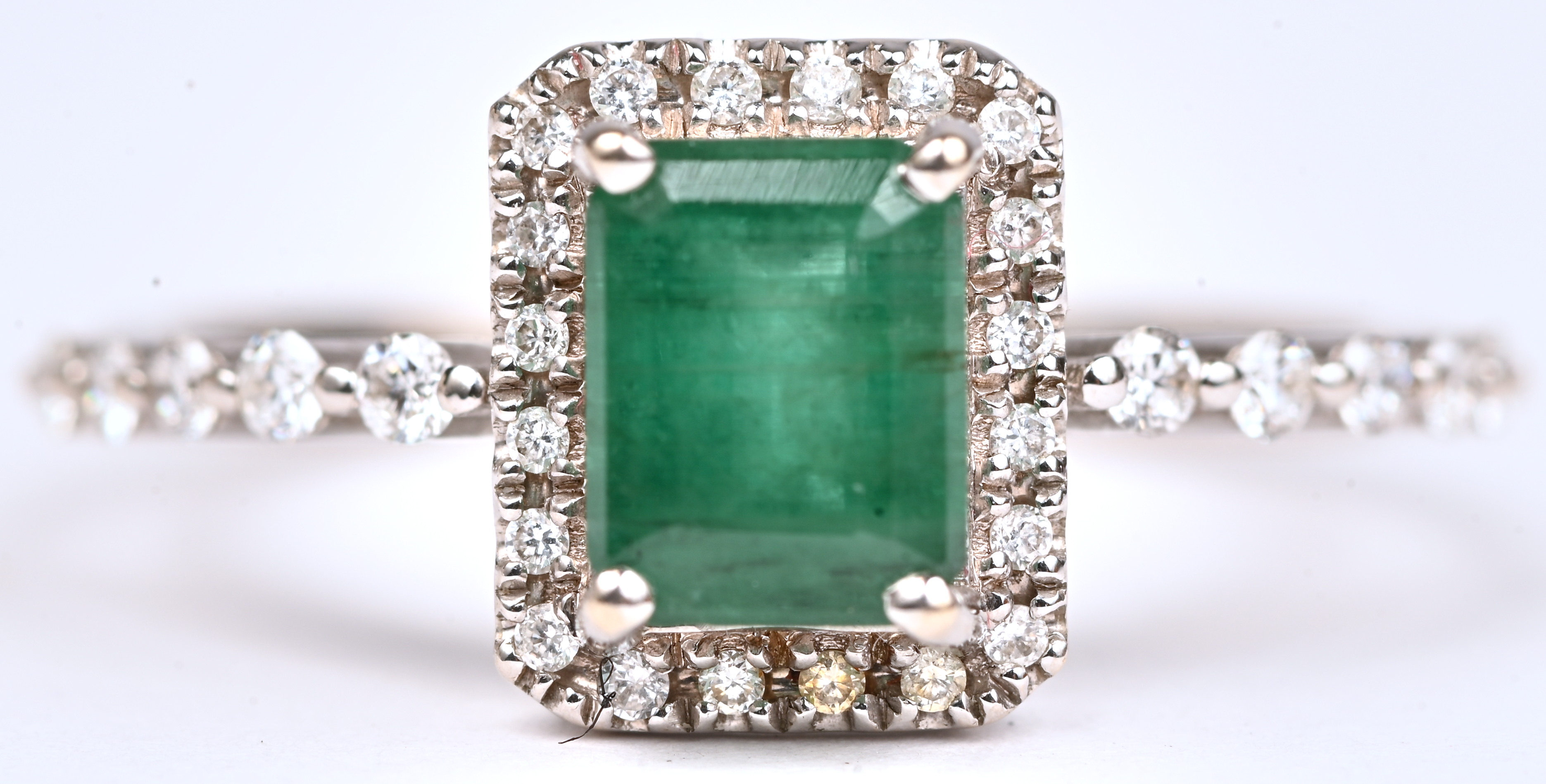 Een 18 kt witgouden ring bezet met een centrale smaragd van +- 0,50 ct. en briljanten met een gezamenlijk gewicht van +- 0,25 ct Een 18 kt witgouden ring bezet met een centrale smaragd van +- 0,50 ct. en briljanten met een gezamenlijk gewicht van +- 0,25 ct.