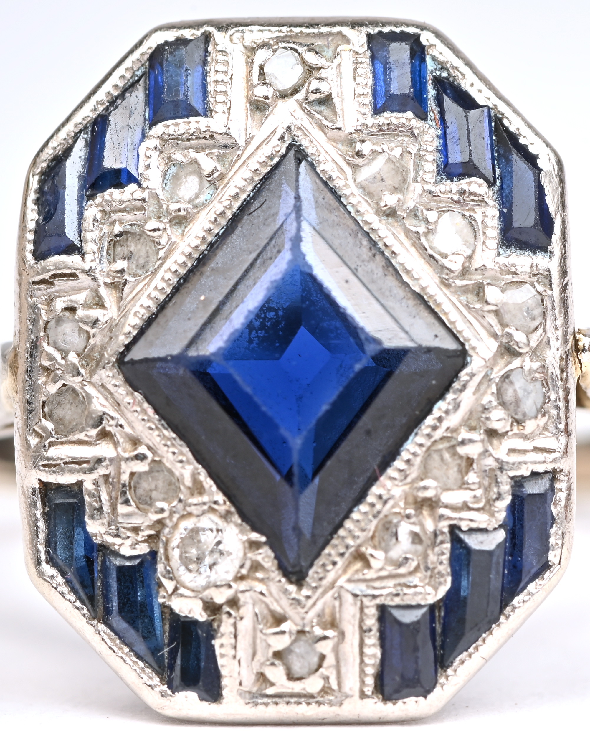 Een 18 kt witgouden art deco ring bezet met diamanten oude slijp met een gezamenlijk gewicht van +- 0,15 ct. en saffieren met een gezamenlijk gewicht van +- 1 ct Een 18 kt witgouden art deco ring bezet met diamanten oude slijp met een gezamenlijk gewicht van +- 0,15 ct. en saffieren met een gezamenlijk gewicht van +- 1 ct.