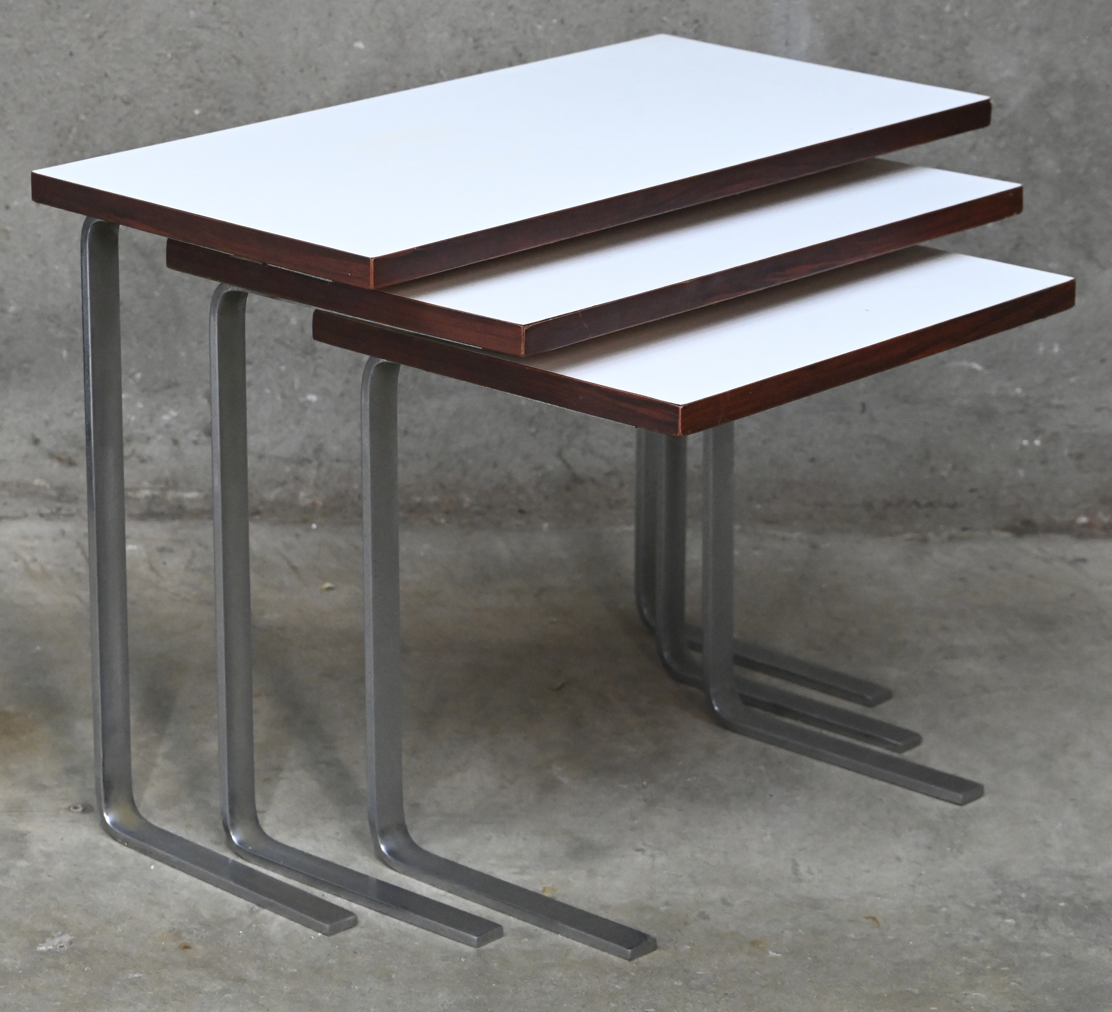 Een set van 3 vintage bijzettafeltjes met formica blad en geborsteld stalen onderstel Een set van 3 vintage bijzettafeltjes met formica blad en geborsteld stalen onderstel.